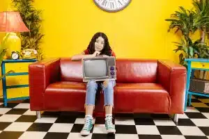 Studio televisivo anni '90 con set di sitcom, luci di scena e un attore in costume durante una registrazione