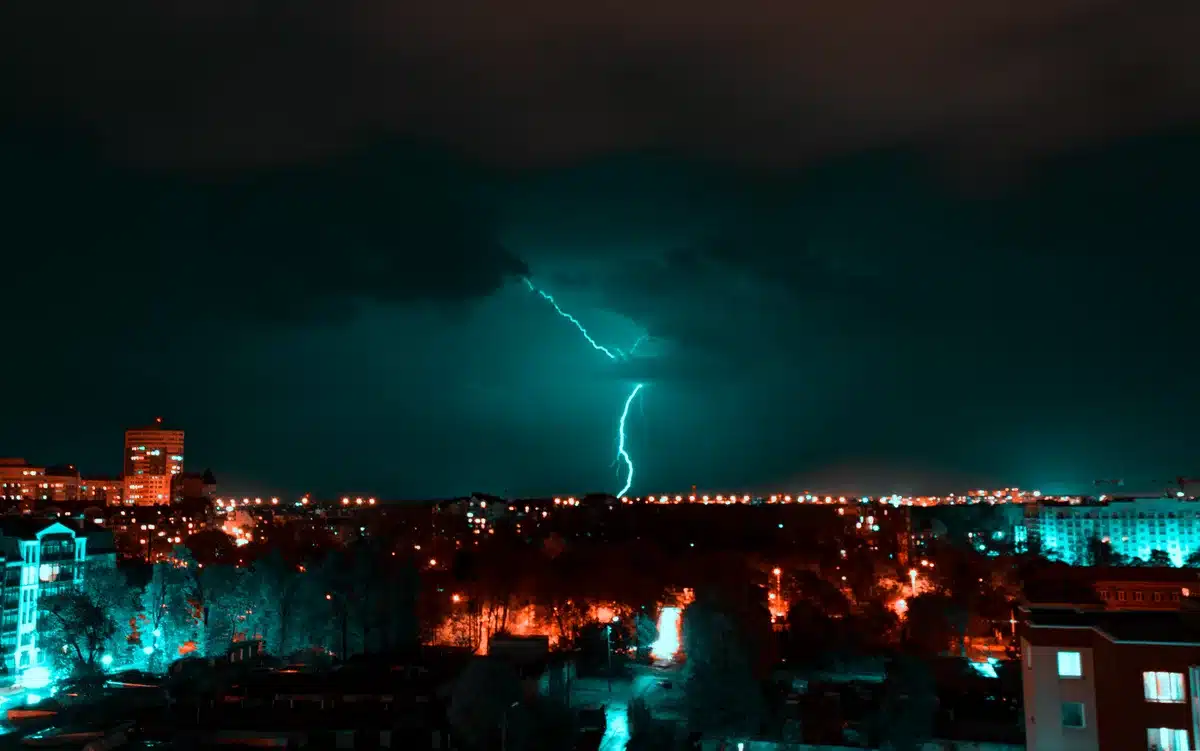 Mostro gigante che distrugge una città illuminata di notte, con figure anonime in fuga