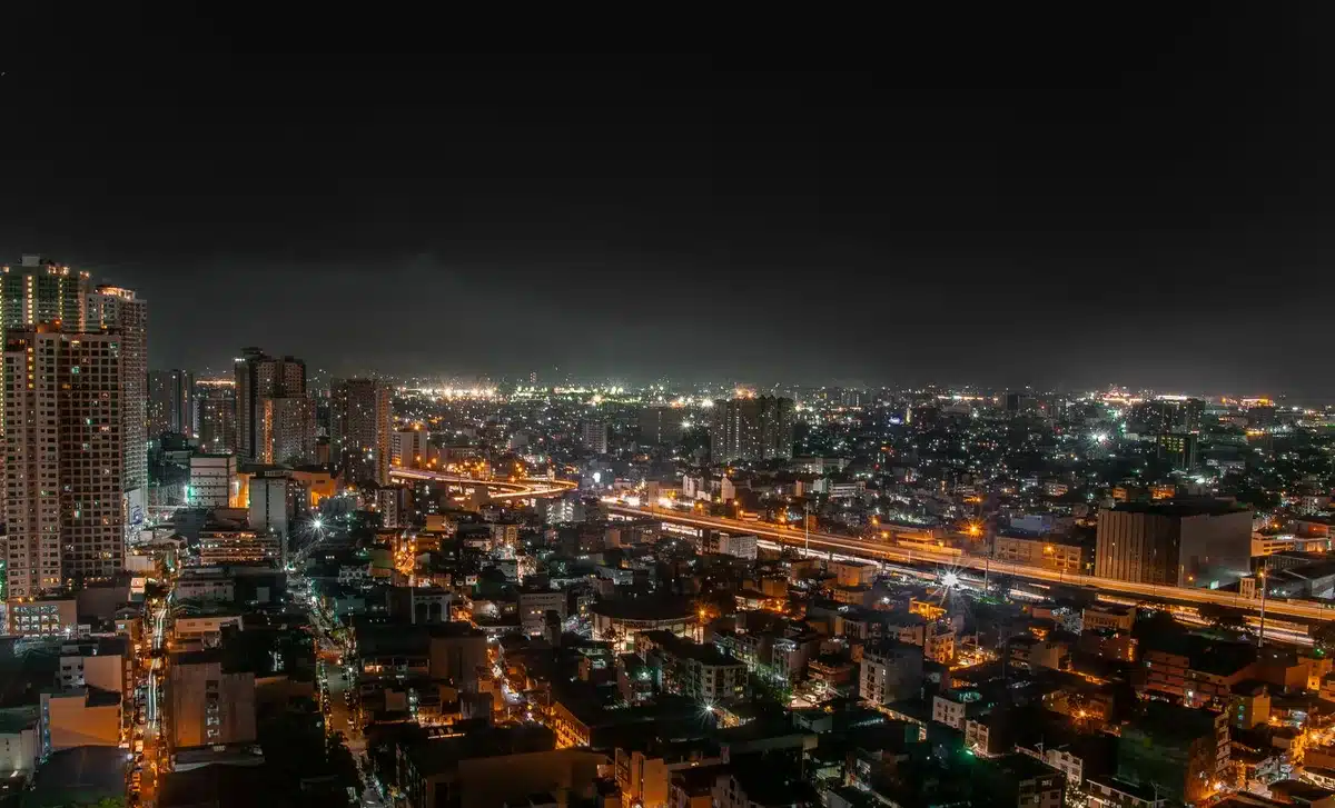 Figura mascherata in costume rosso e blu su un tetto urbano con la città illuminata sullo sfondo