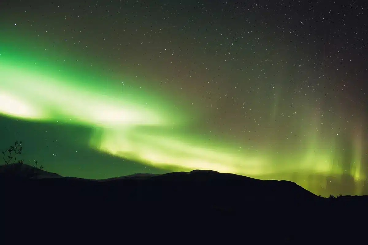 Persone illuminate da una luce verde brillante che splende nel cielo notturno