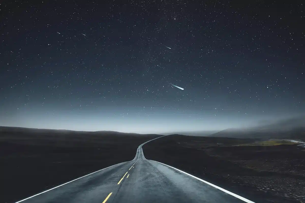 Strada innevata buia di notte con auto in viaggio, nebbia e scarsa visibilità