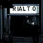 Pubblico in sala visto di profilo con lo schermo luminoso sullo sfondo