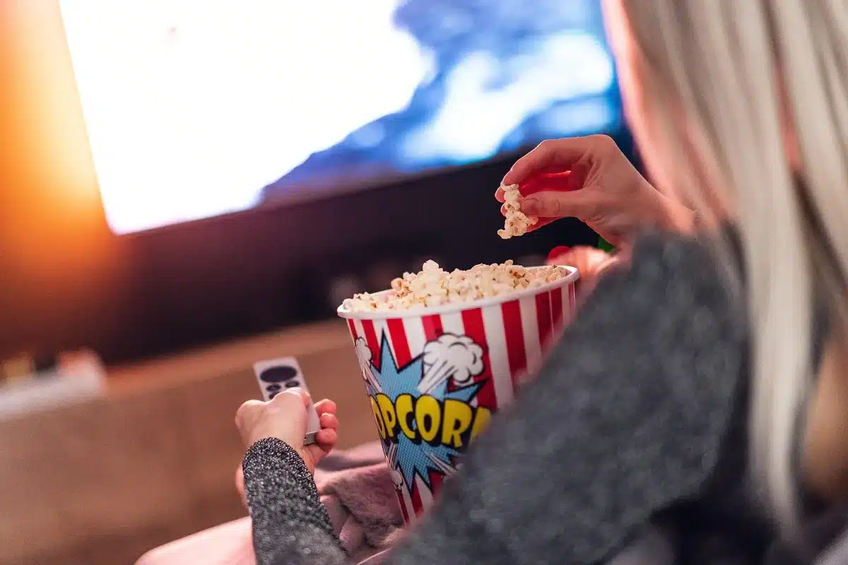 Persone sul divano che guardano una maratona TV con popcorn