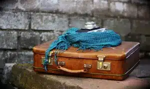 Sagoma di donna vicino a una giacca appesa e una valigia in una stanza, atmosfera da thriller