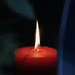 Bicchiere di whiskey su tavolo con carte e candela, atmosfera tesa