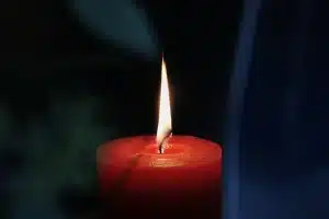 Bicchiere di whiskey su tavolo con carte e candela, atmosfera tesa