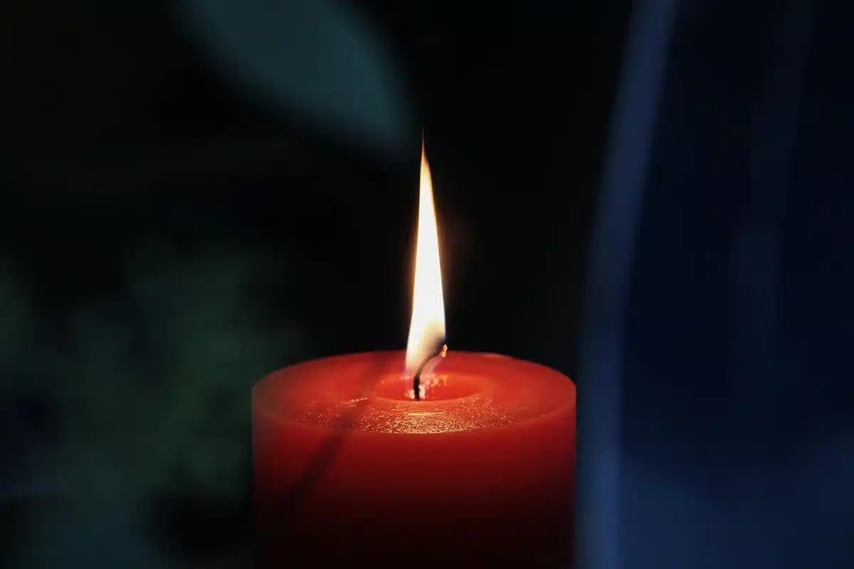 Bicchiere di whiskey su tavolo con carte e candela, atmosfera tesa