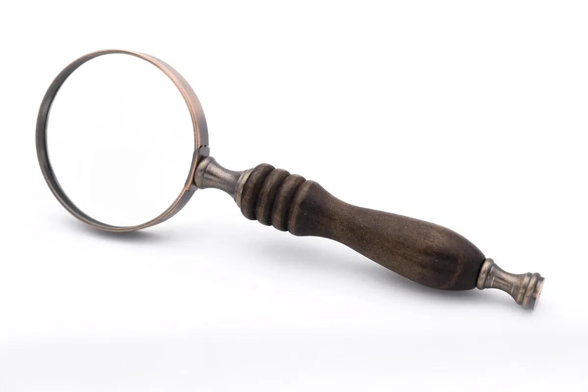 Scrivania d'epoca con lente d'ingrandimento e appunti che evocano il lavoro investigativo