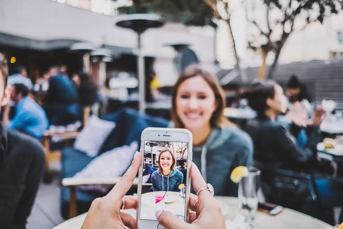 Due smartphone su un tavolo da caffè con mani silhouettate e folla sfocata sullo sfondo