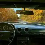 Due valigie vicino a un'auto al tramonto che suggeriscono un viaggio verso la libertà
