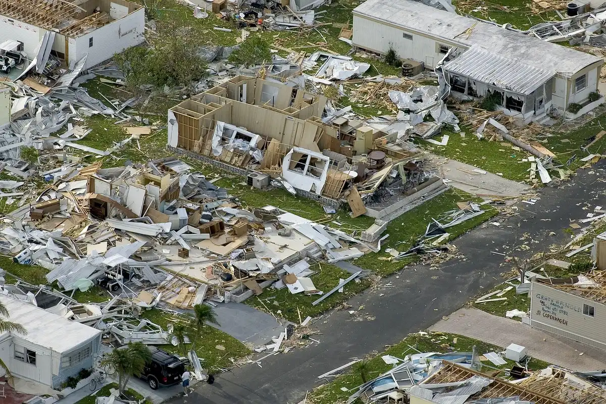 Figure anonime che avanzano in un quartiere deserto con case danneggiate
